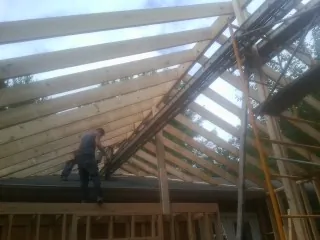 Rafters going up over a new addition with a worker on the wall in Hope
